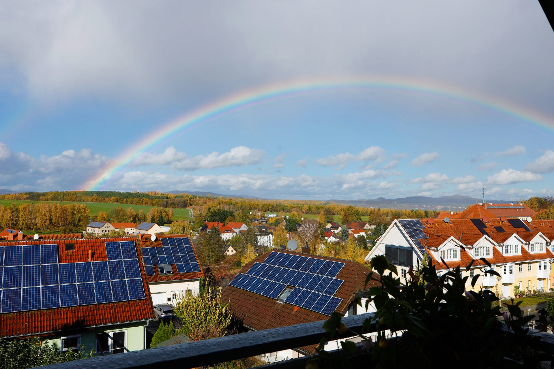 Arcoíris sobre un barrio suburbano con paneles solares.
